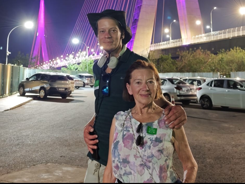 Benjamin Kempin com acompanhante à noite em frente à ponte iluminada